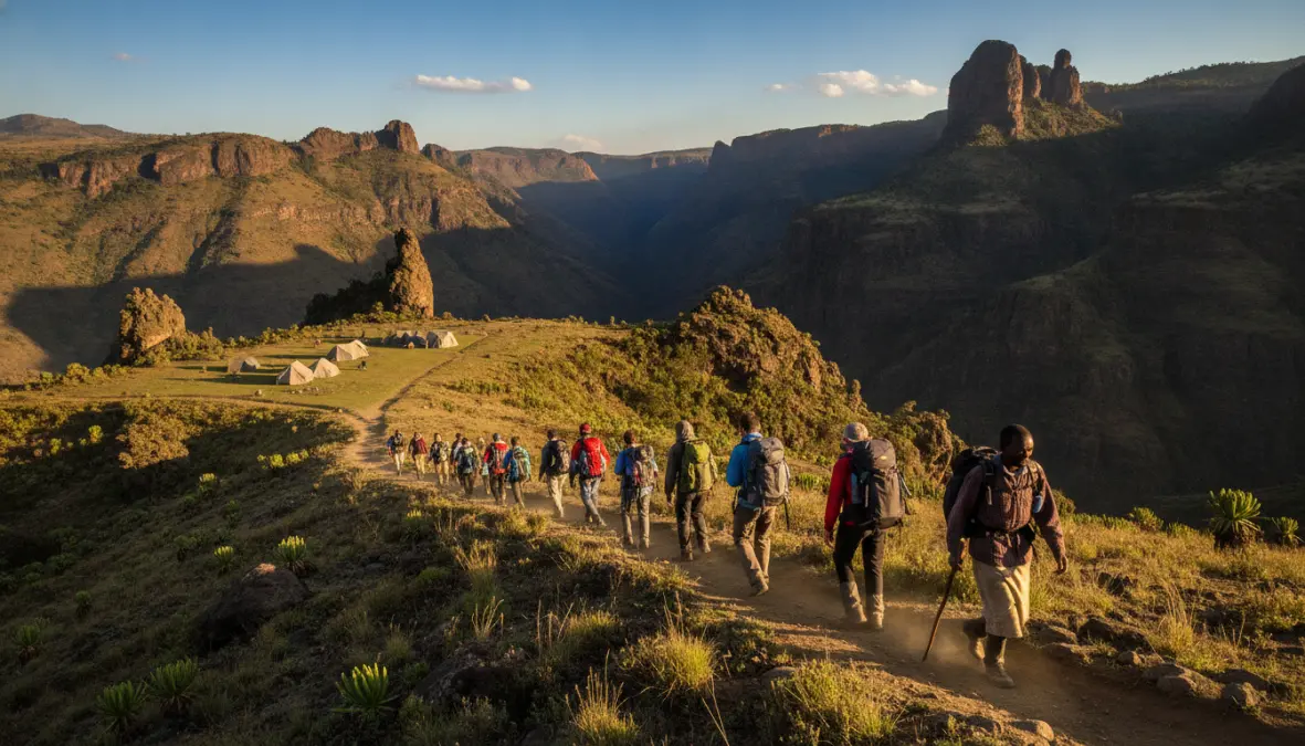 Hikers trekking Simien Mountains trail toward Chenek camp in Ethiopian highlands